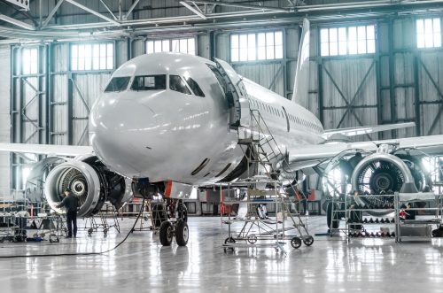 Luft- und Raumfahrtindustrie - Passagierflugzeug bei der Reparatur von Triebwerk und Rumpf im Flughafen-Hangar